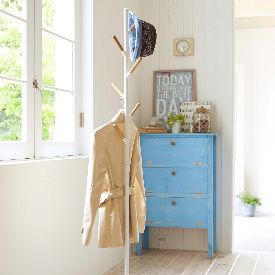 Coat Rack by Yamazaki Home in white supporting a coat and a hat.