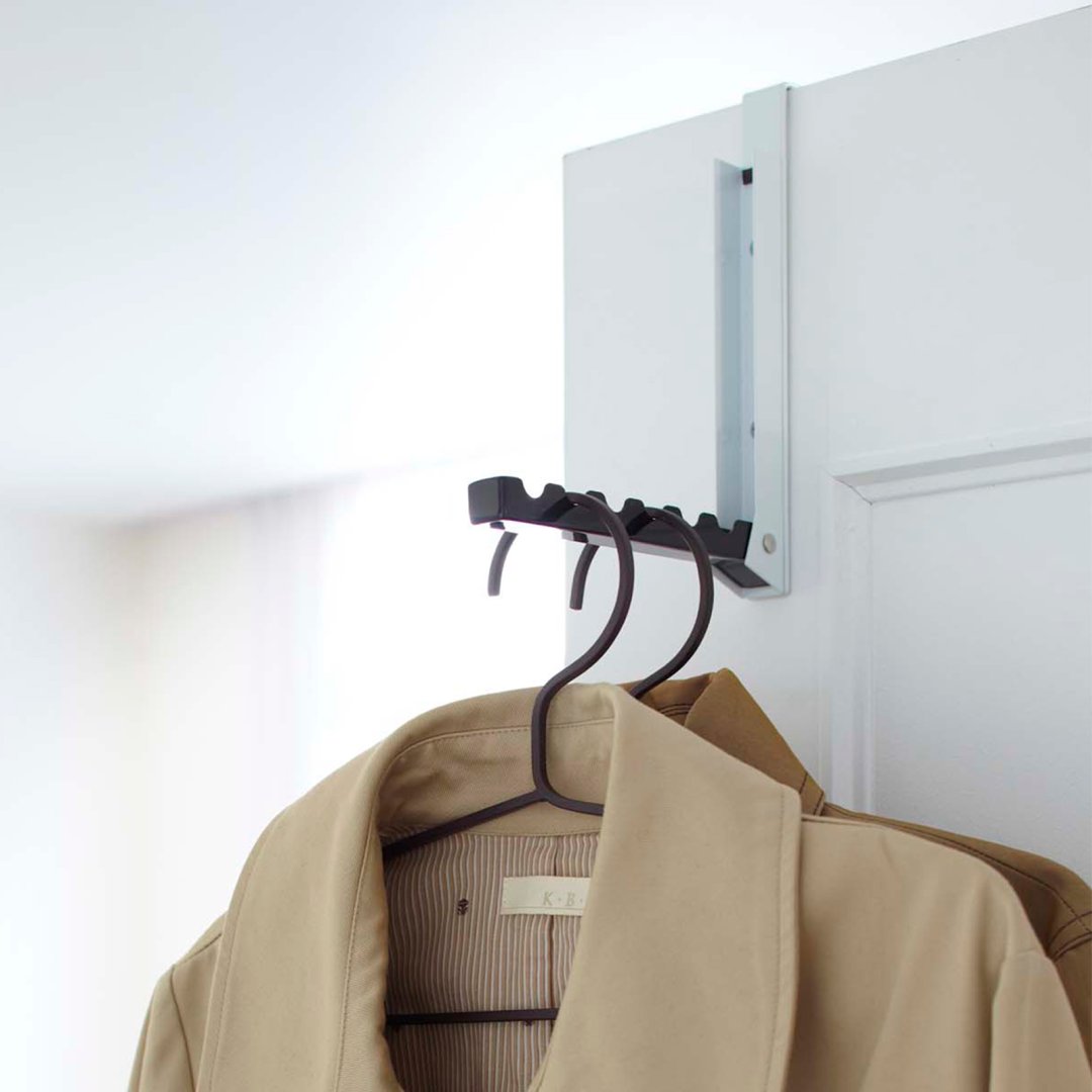 Yamazaki Home White Over-the-Door Hook on a door holding 2 hanging jackets.