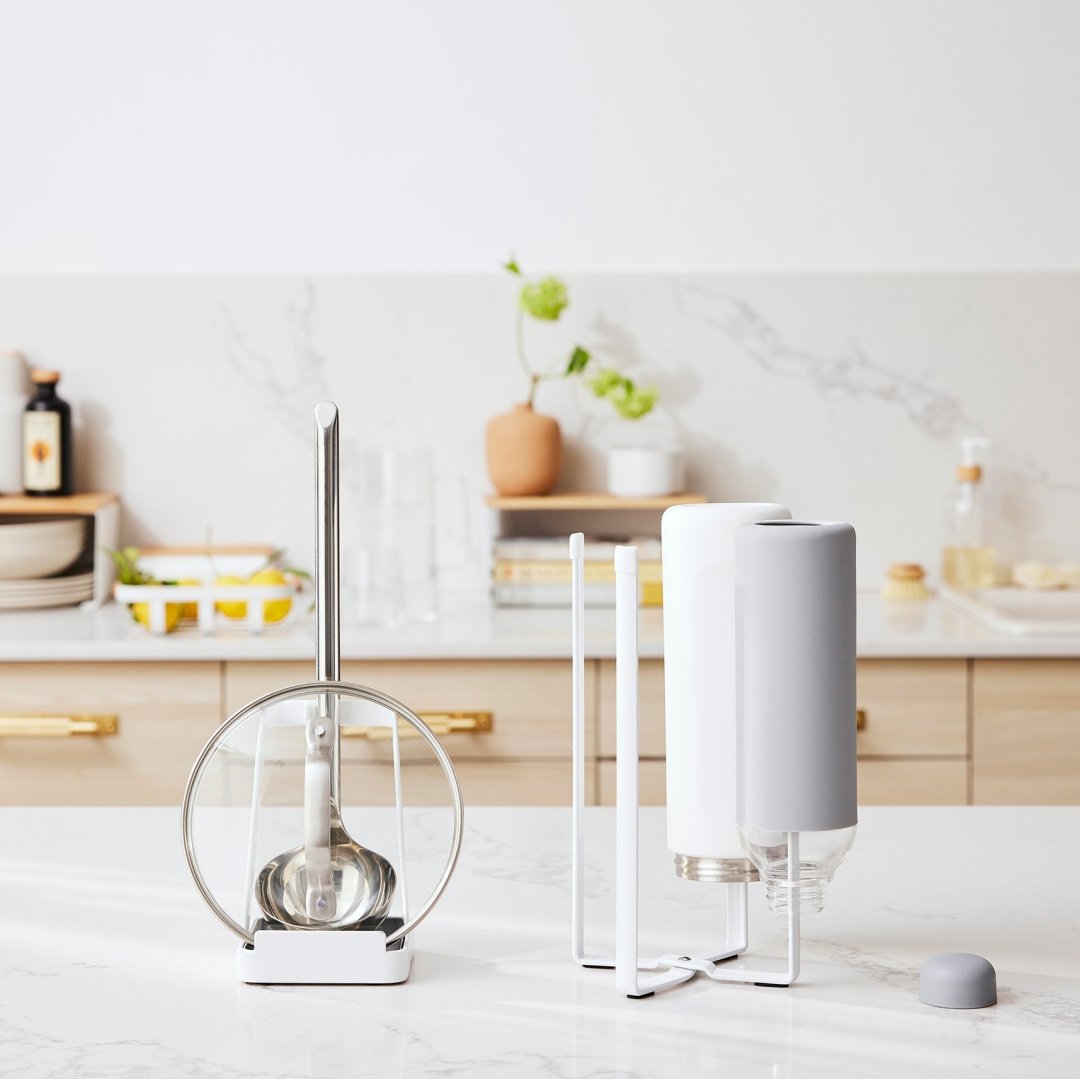 Lid & Ladle Stand and Collapsible Bottle Dryer by Yamazaki Home in white on a kitchen countertop.