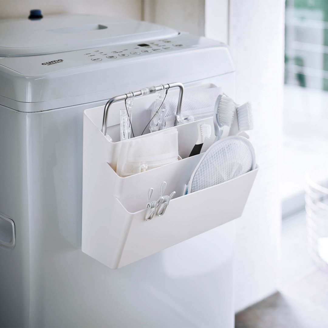 Yamazaki Home white Magnetic Storage Caddy attached to washing machine holding laundry items.