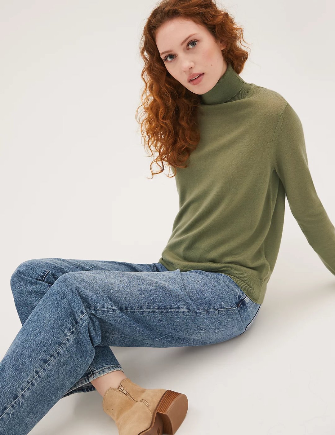 Woman in olive green turtleneck sweater with mom jeans and ankle boots
