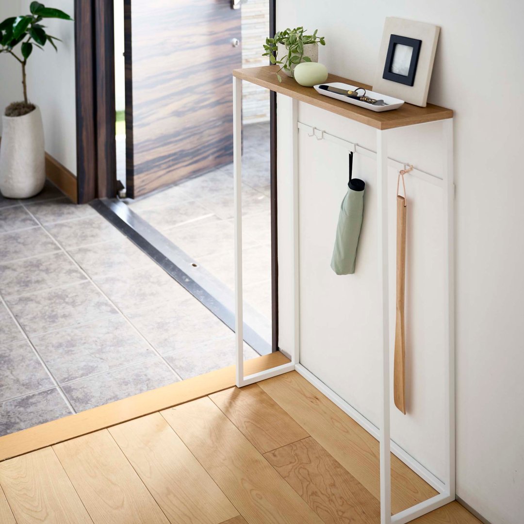 slim console table in home entryway with umbrella and shoe horn hanging
