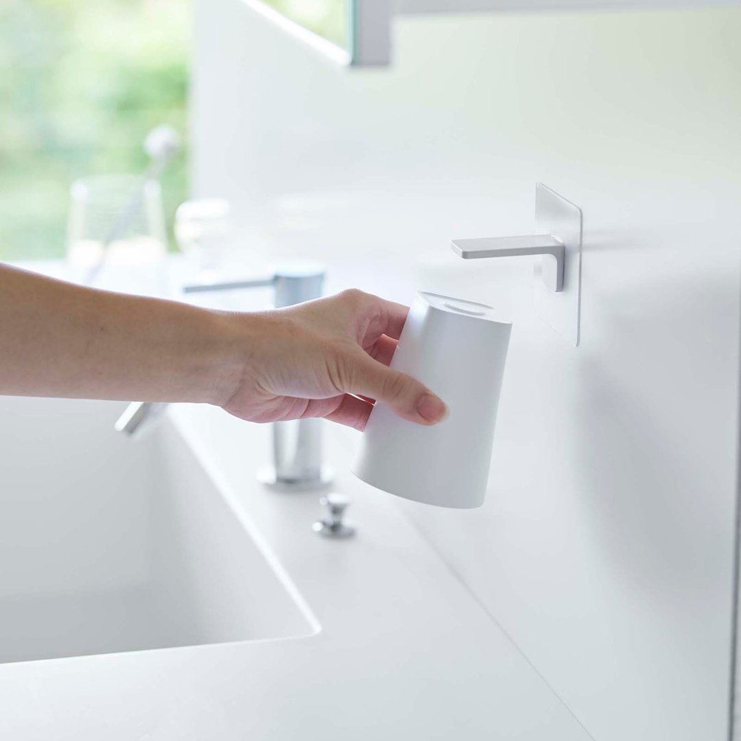 hand reaching for magnetic cup attached to mirror